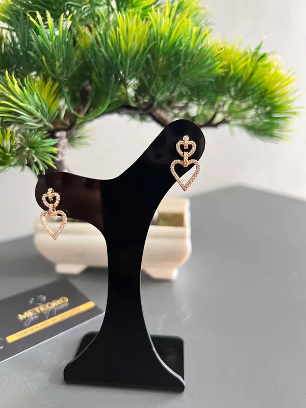 Brincos Corações Duplos. Dois corações vazados em dourado, com detalhes brilhantes.