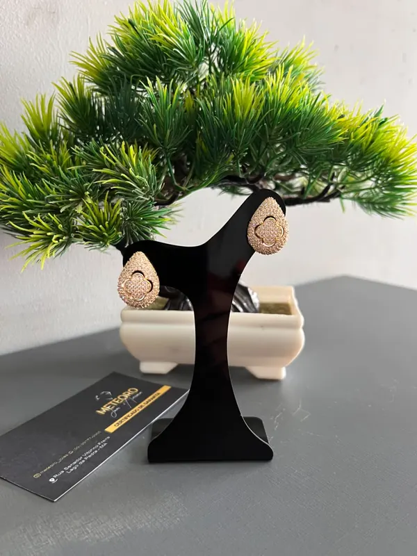 Brincos Gota Trevo. Formato de gota com detalhe central em trevo e brilho delicado.